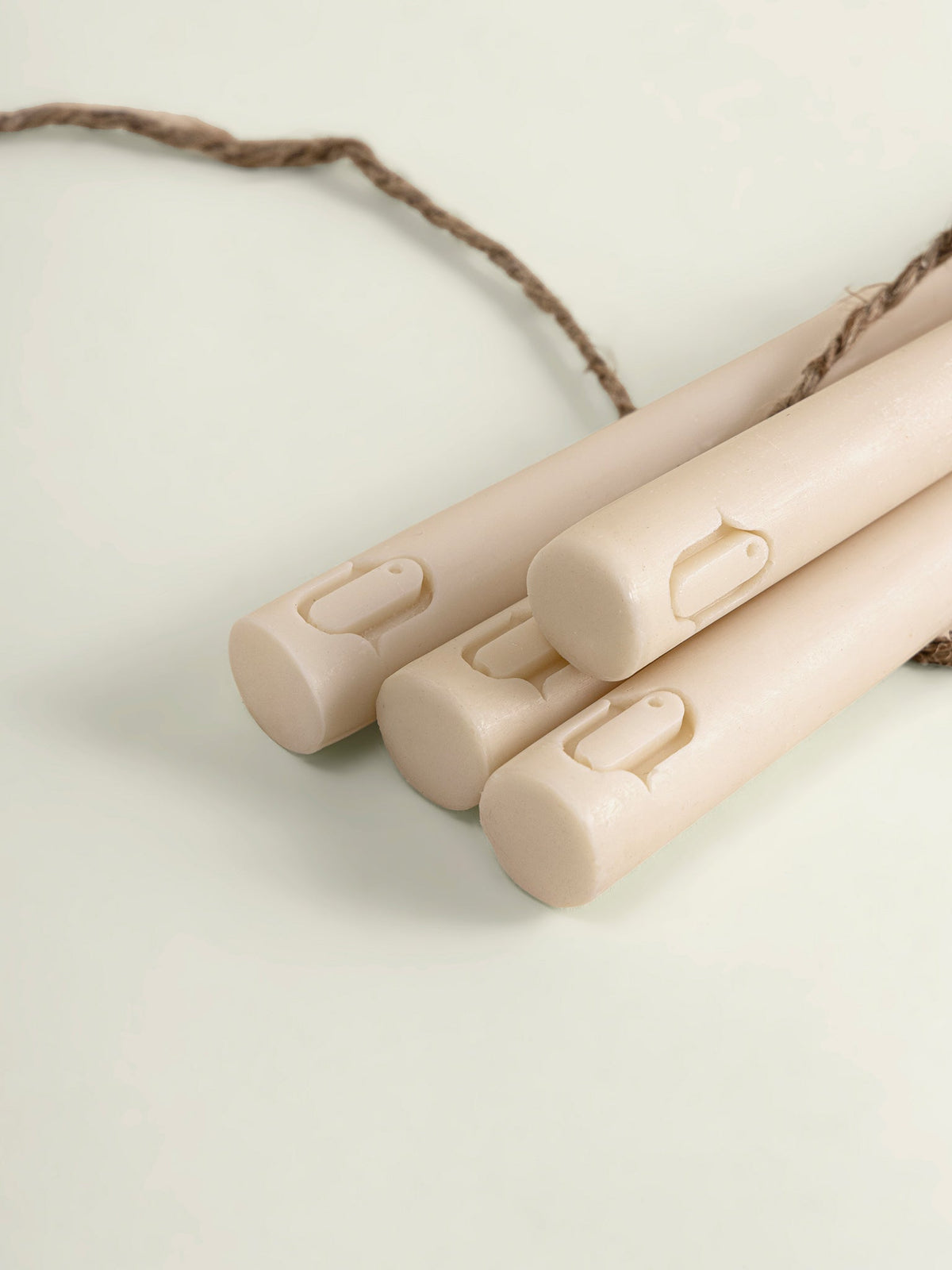 Close-up of a set of beige taper candles with logo of 'anctuar' and a brown twine cord, photographed on a clean off-white background.