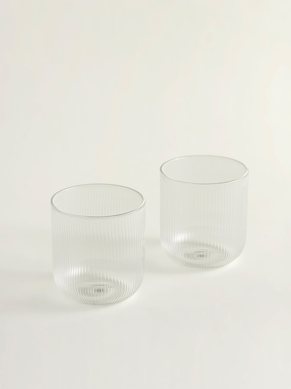 Two clear ribbed glass tumblers on a clean white background.