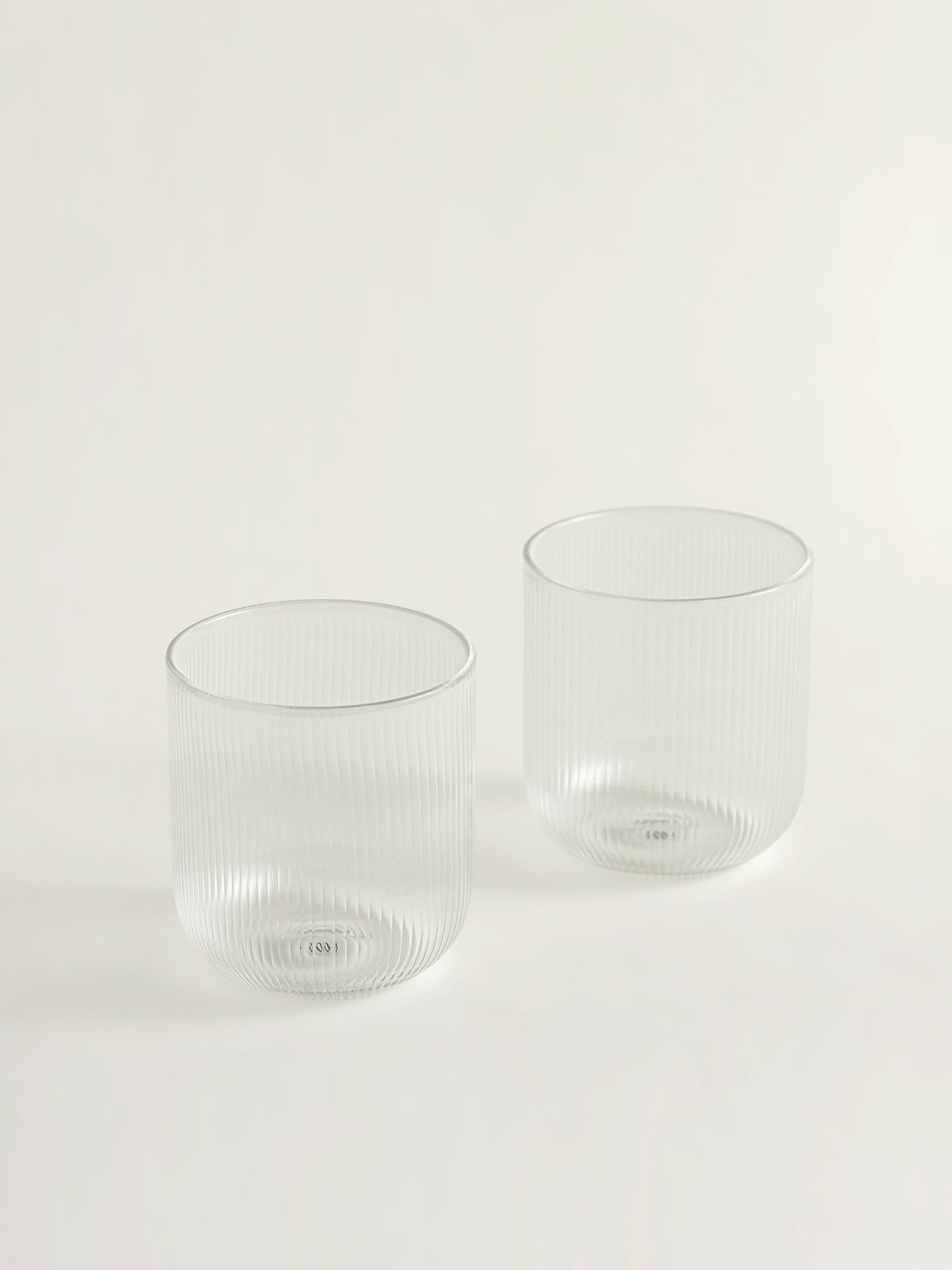 Two clear ribbed glass tumblers on a clean white background.