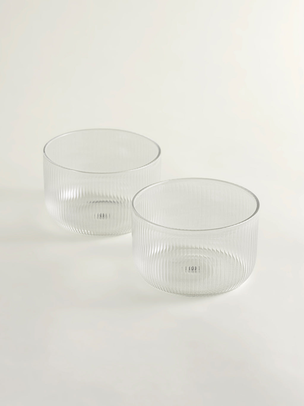 Two clear ribbed glass bowls on a seamless white background.