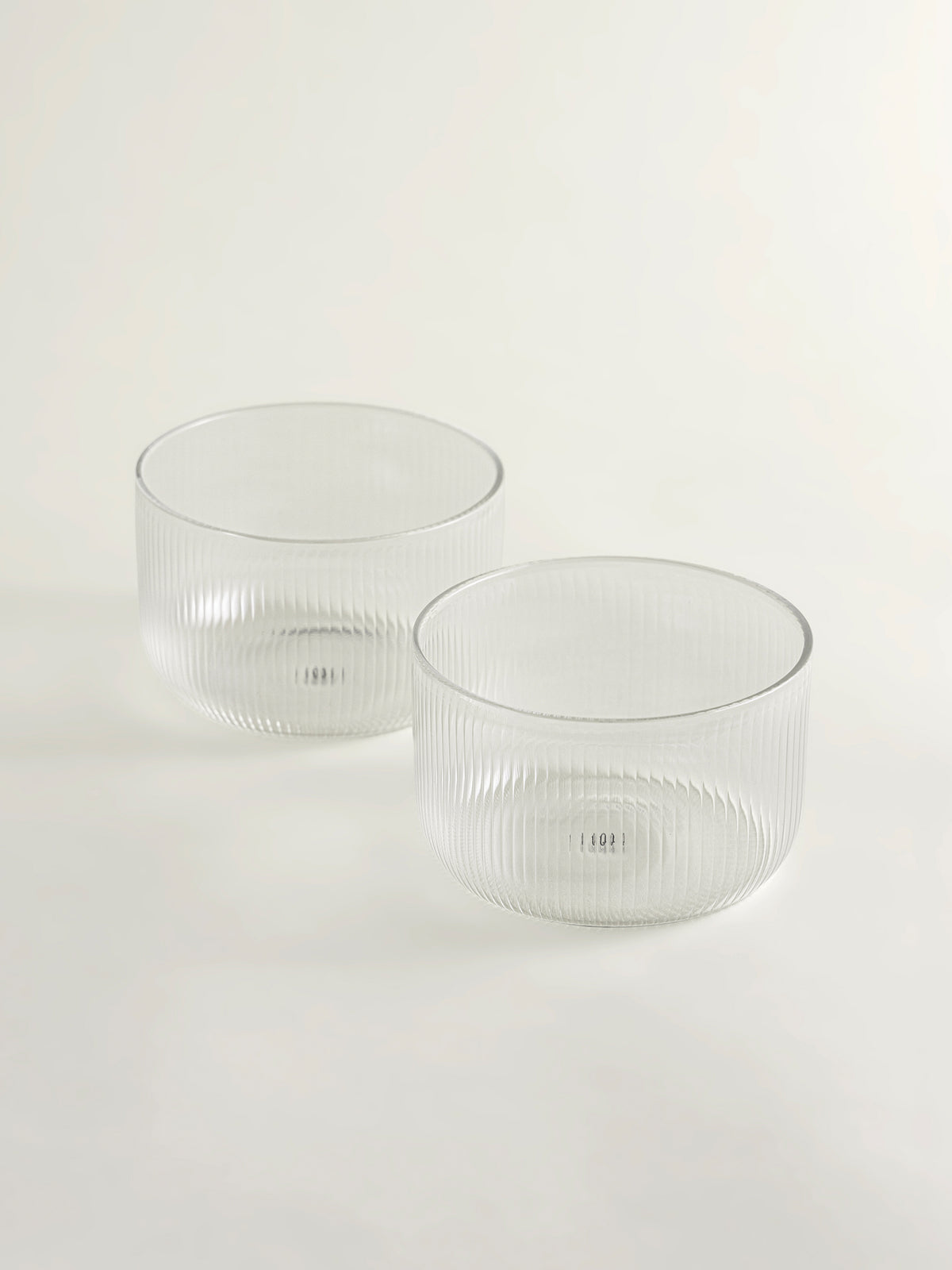 Two clear ribbed glass bowls on a seamless white background.