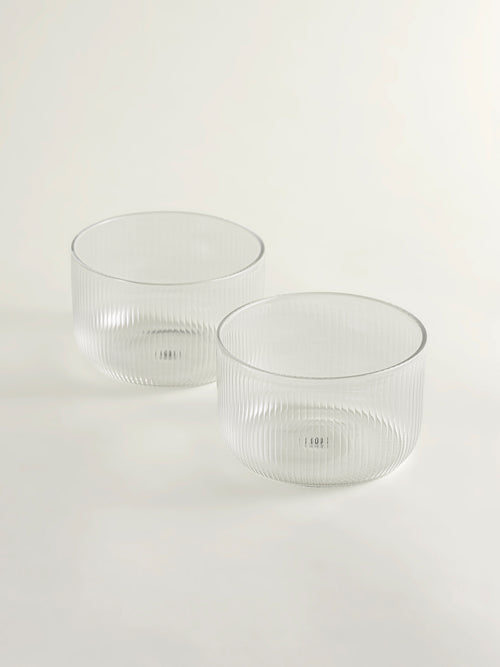 Two clear ribbed glass bowls on a seamless white background.