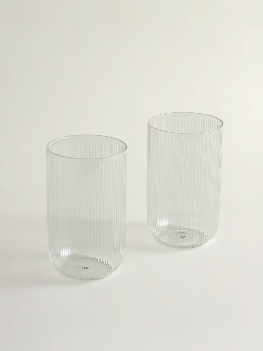 Two clear ribbed glass tumblers on a clean white background.