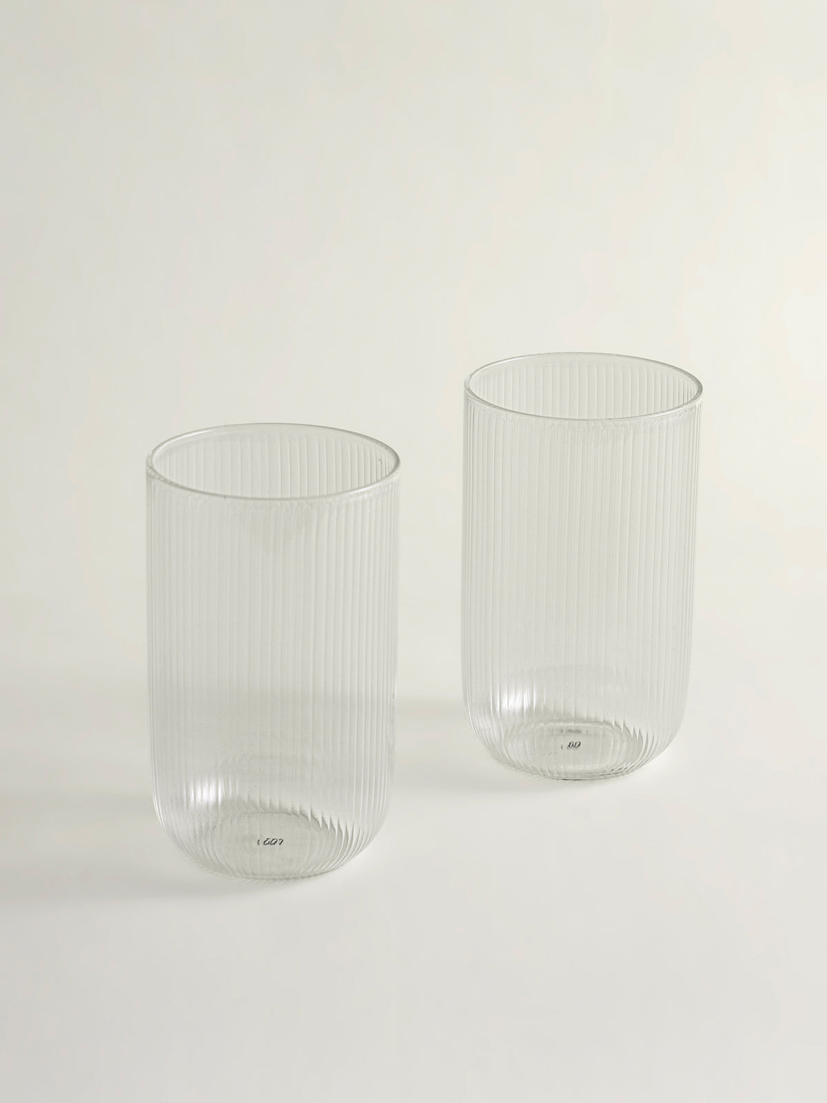 Two clear ribbed glass tumblers on a clean white background.