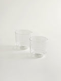 Two clear glass tumblers with a slightly tapered shape, standing on a plain white surface against a white background.