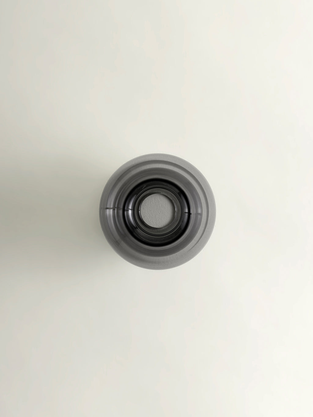 A top-down view of a grey matcha whisk holder, set against a plain off-white background.