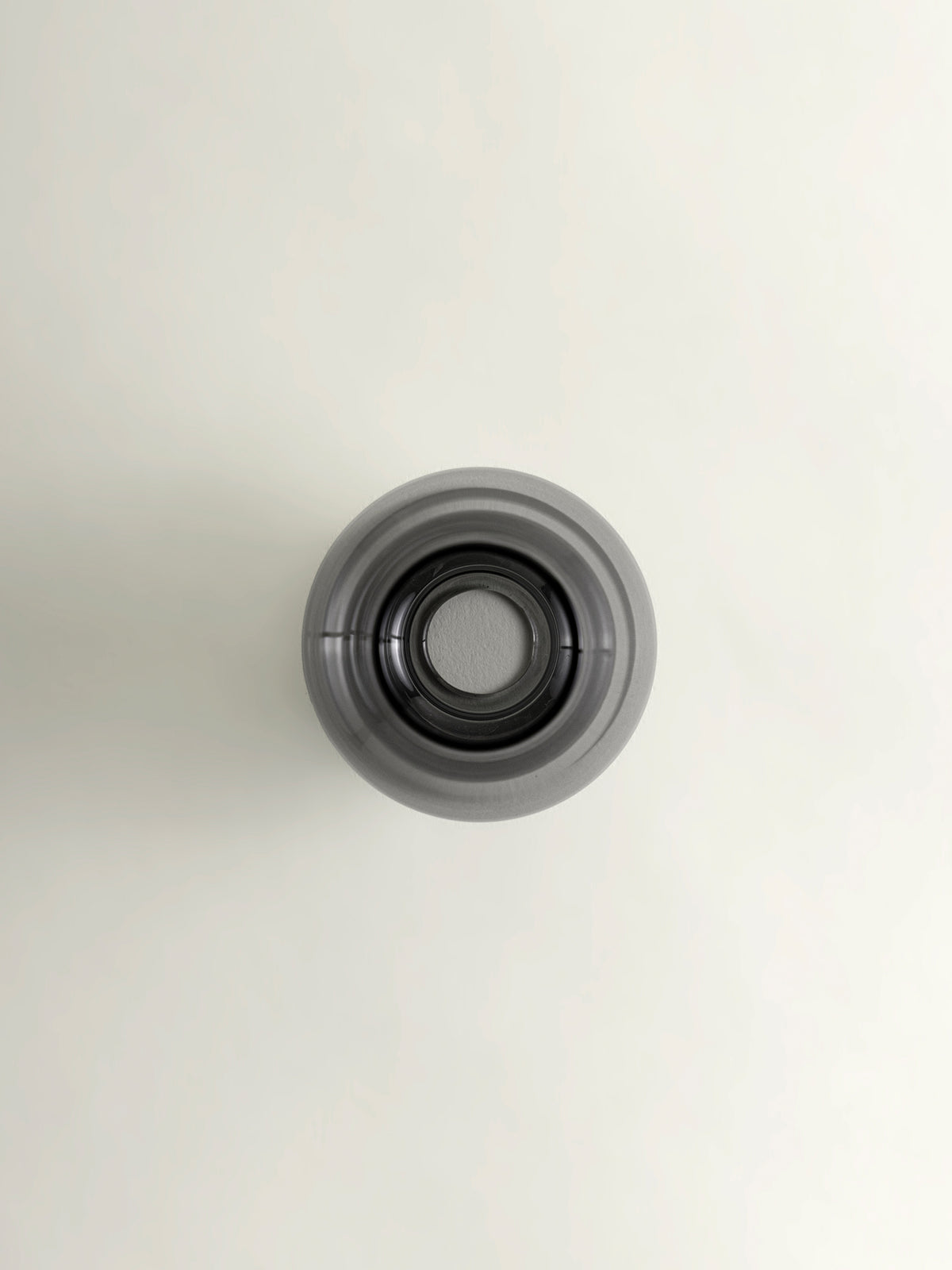 A top-down view of a grey matcha whisk holder, set against a plain off-white background.
