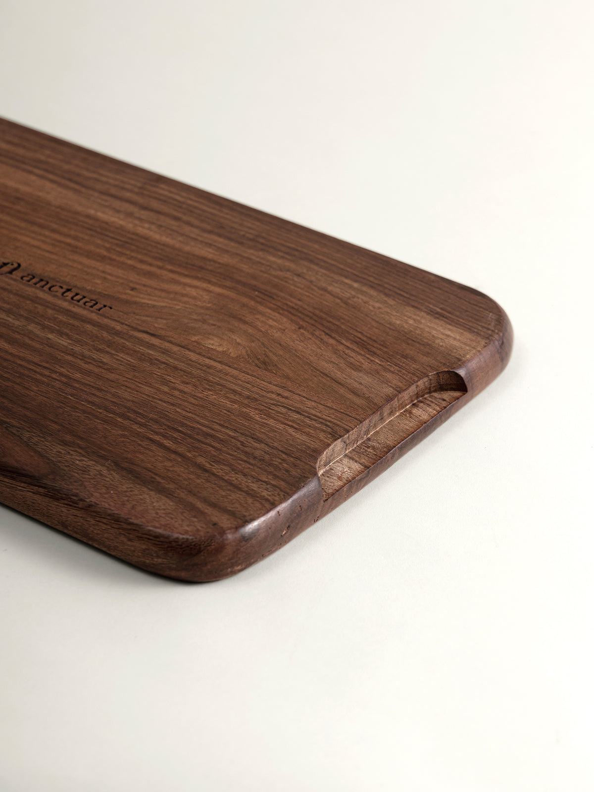 A close-up of a dark brown rosewood tray with rounded corners and a cutout handle, featuring the engraved brand name 'anctuar' on a clean white background.